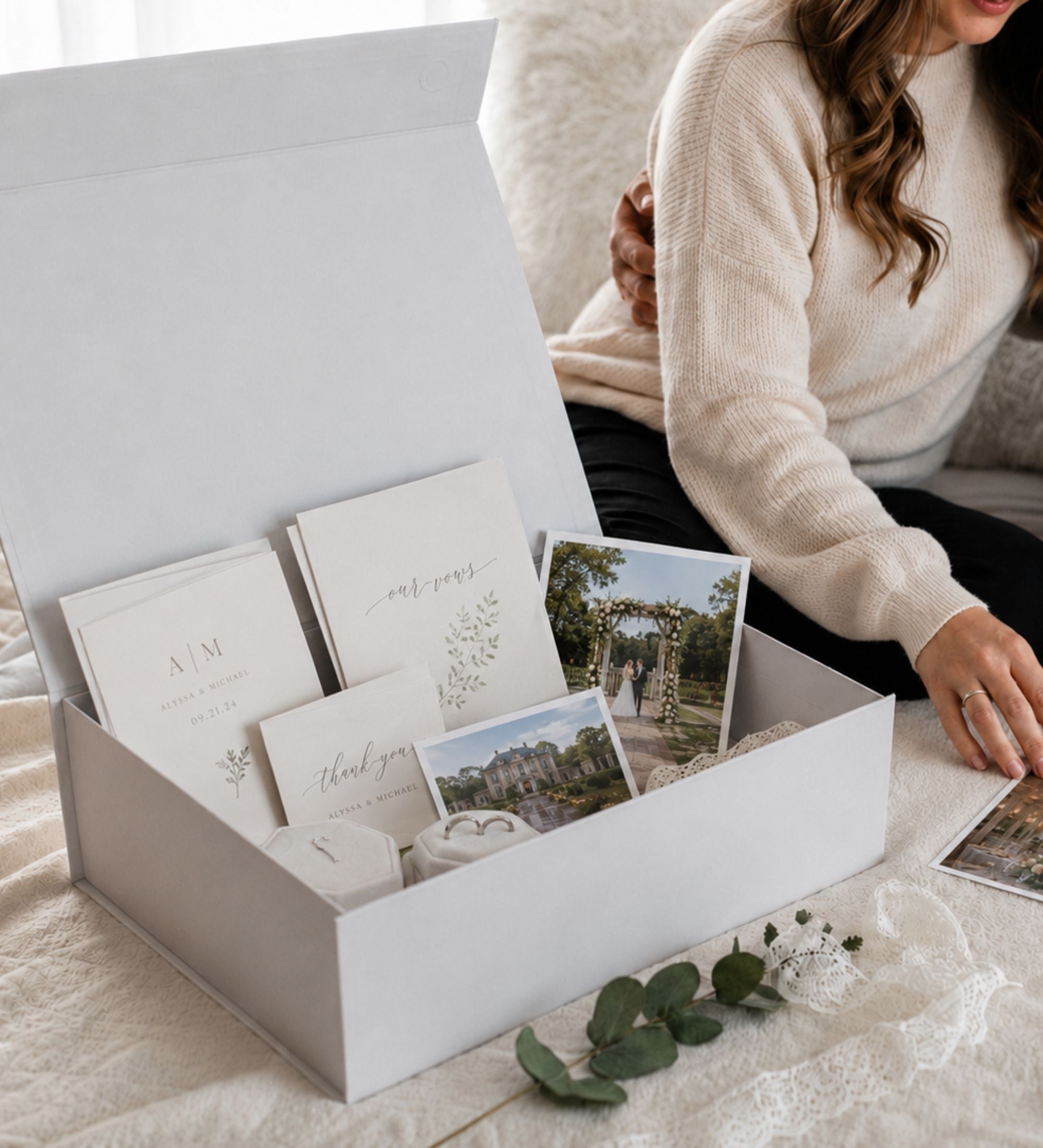 Open keepsake box holding wedding vow books, printed photographs, thank you cards and velvet ring boxes
