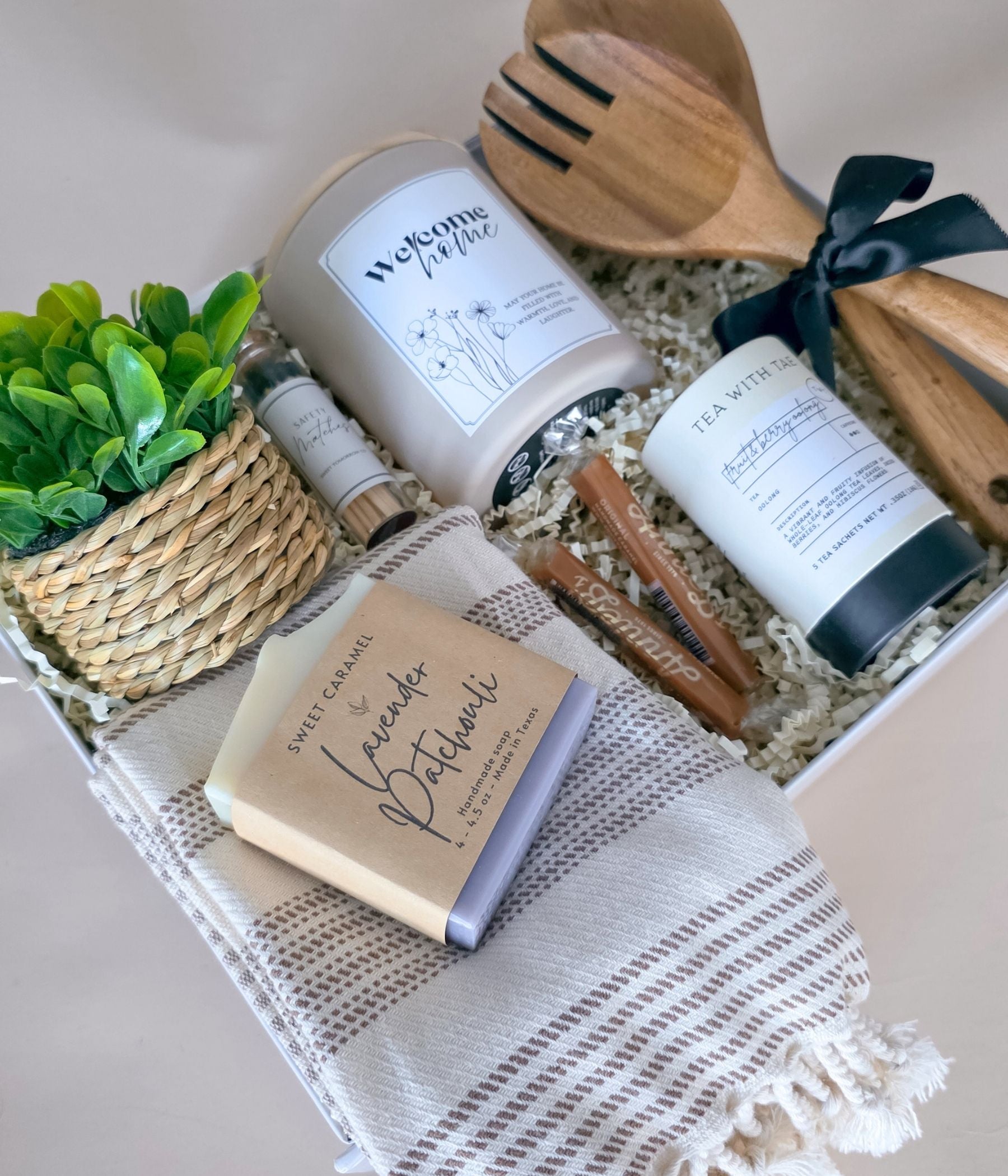 Deluxe housewarming gift basket with welcome home candle, tea, towel, matches, and caramels in a white magnetic gift box