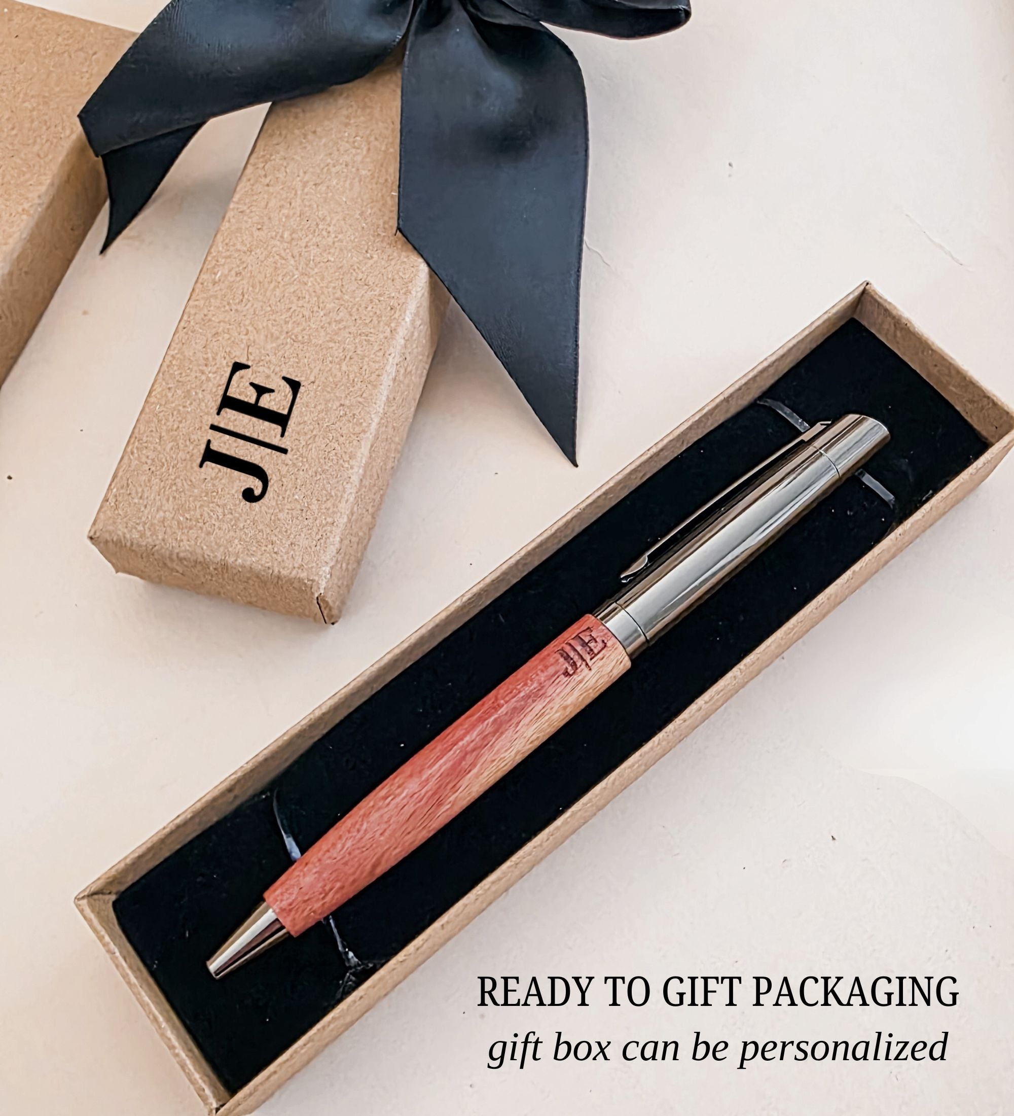 Wood pen with gunmetal cap and etched initials seated in an open gift box lined with black velvet