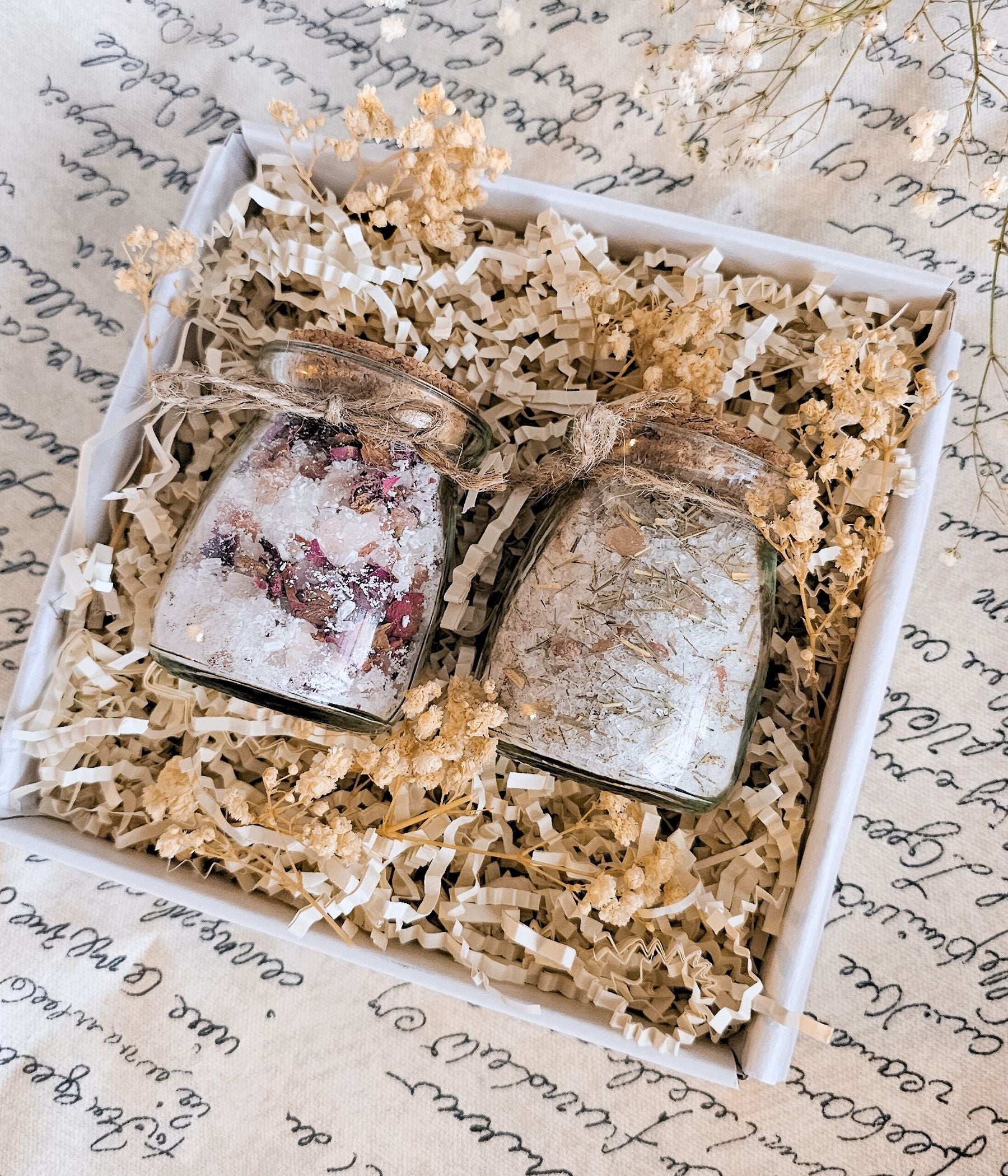 Two botanical bath salt jars styled inside a soft pink spa gift presentation