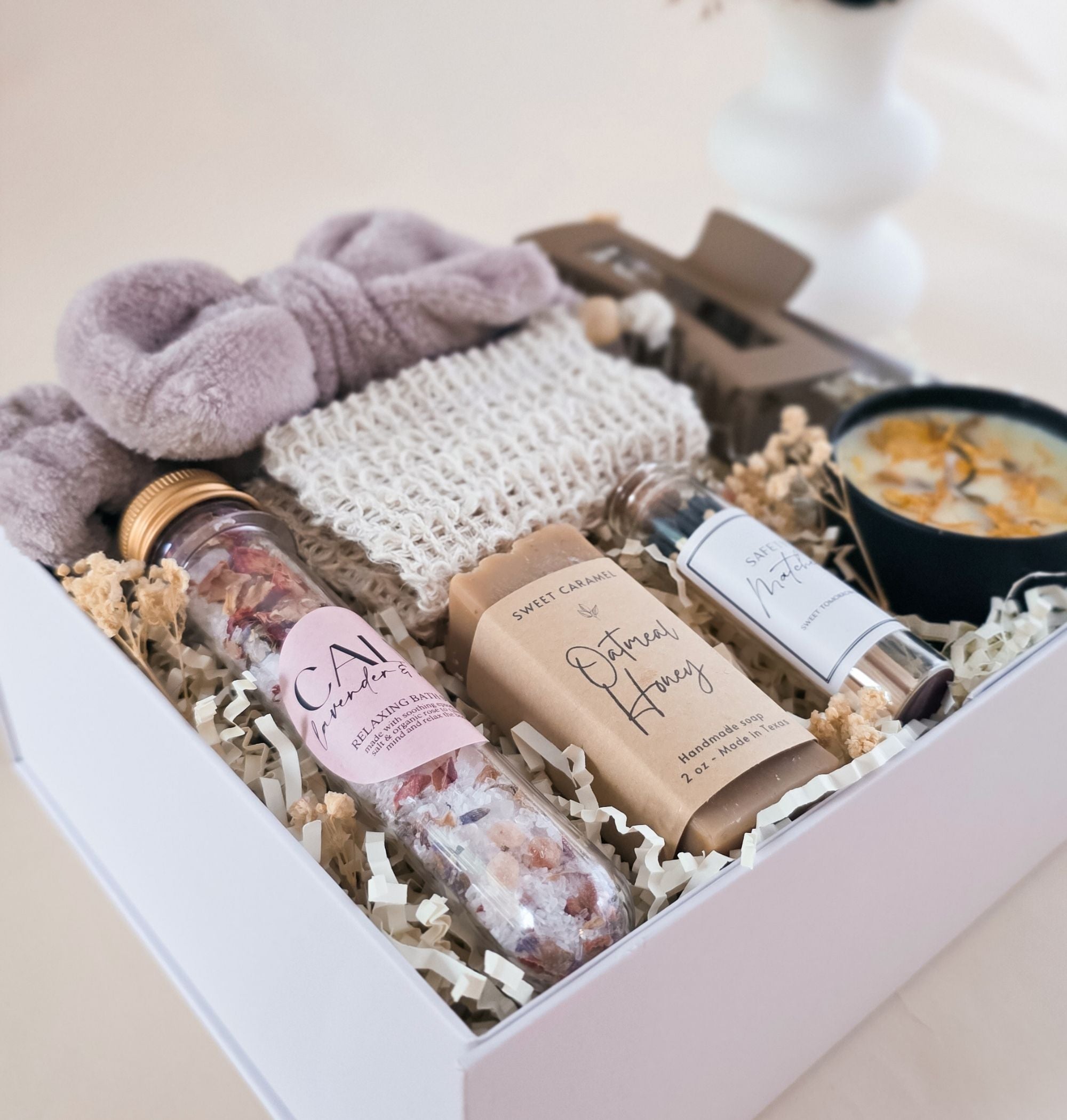 All Botanical Box items arranged individually on neutral background: candle tin, soap bar, sisal sleeve, bath soak tube, spa headband, hair clip, glass jar matches