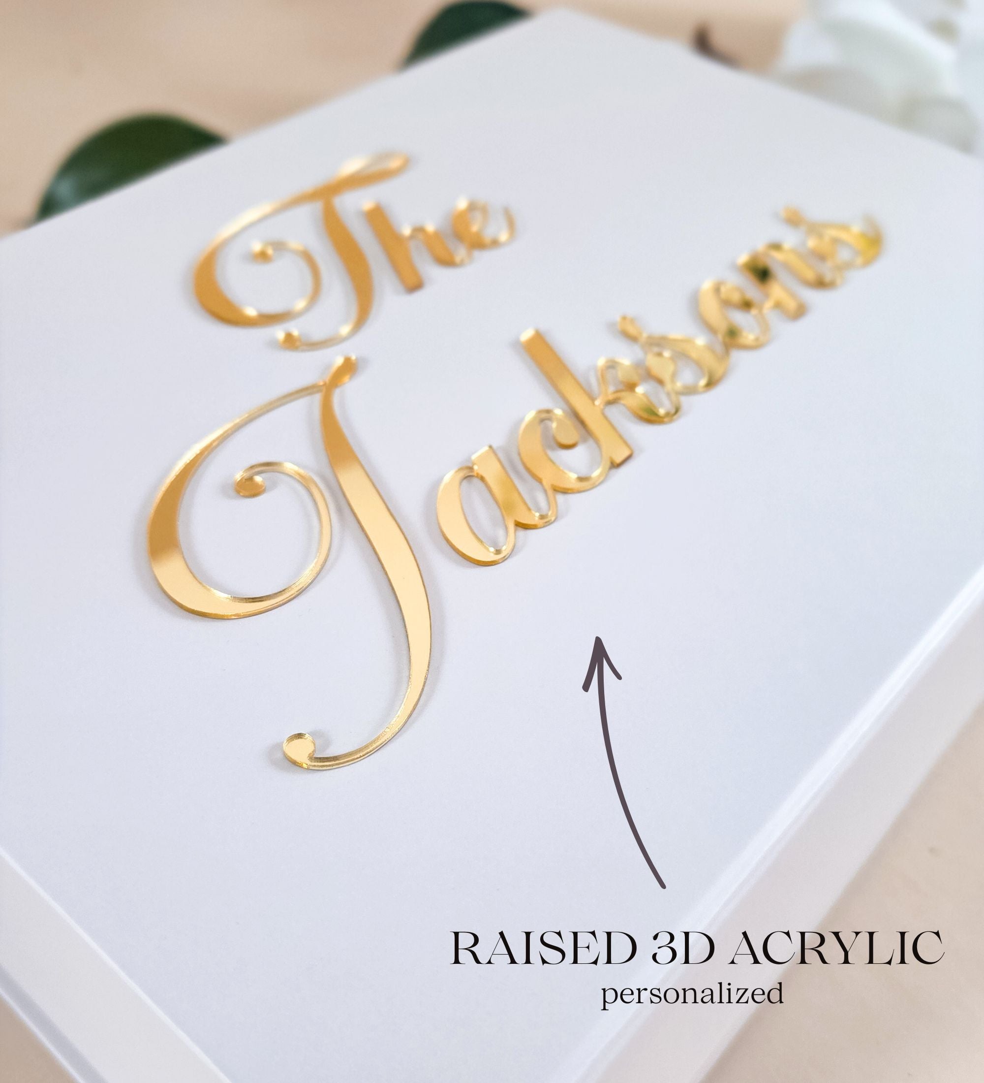Close detail of raised 3D gold acrylic lettering on the matte white lid, showing the dimensional edge