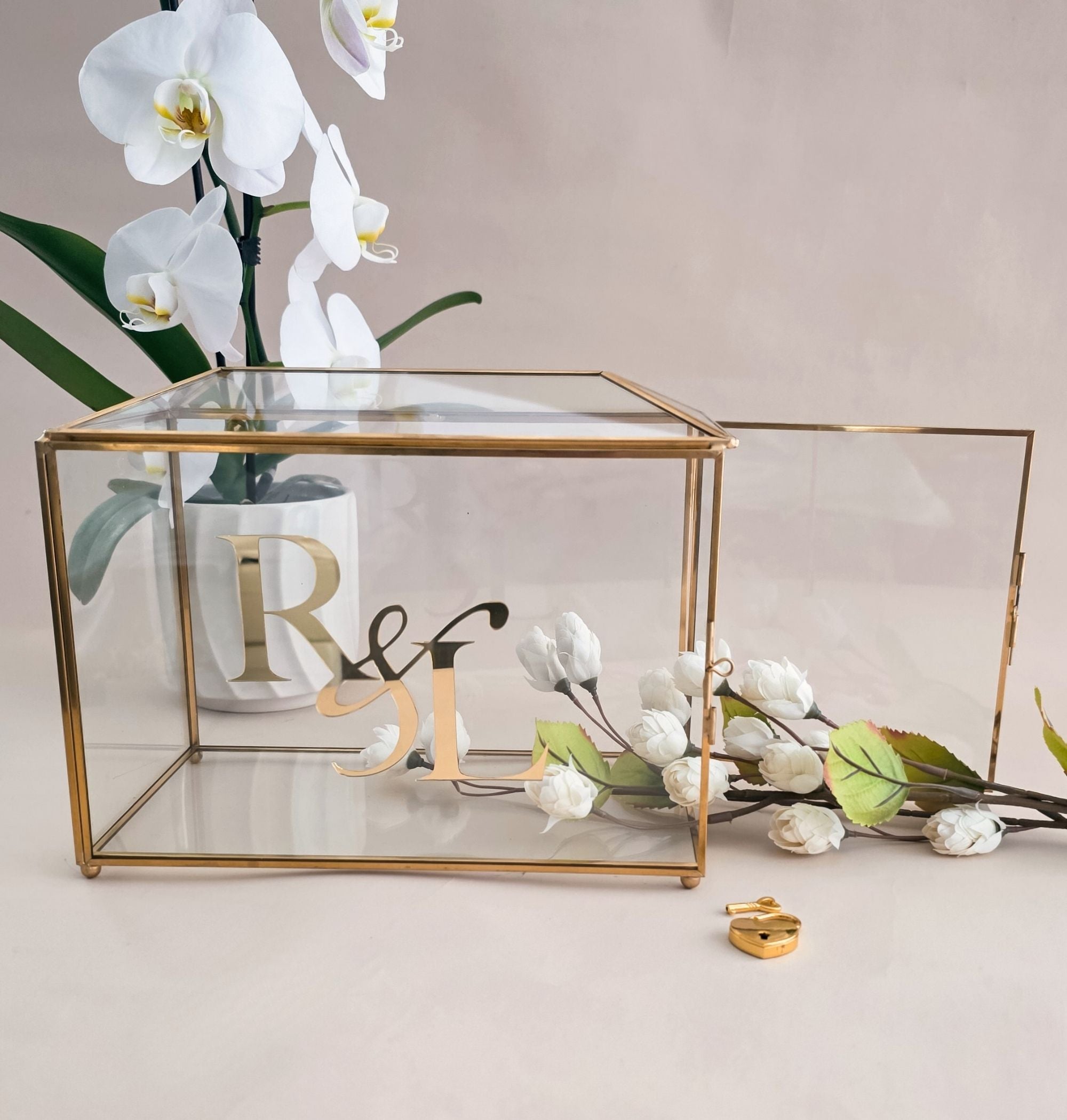 Decorative glass box with gold accents and floral elements on a light background
