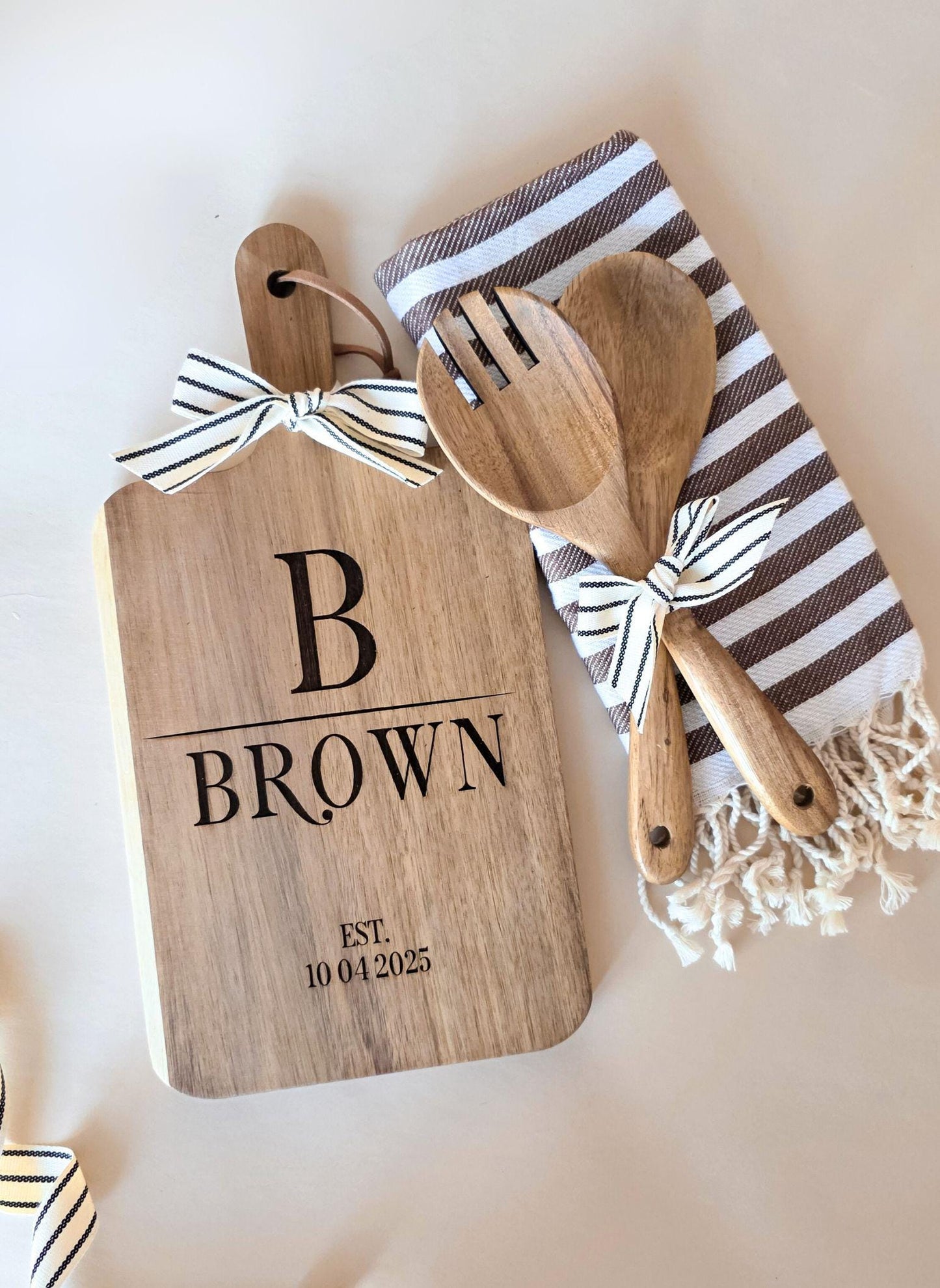Personalized housewarming gift set with engraved cutting board, utensils, and towel — monogram design