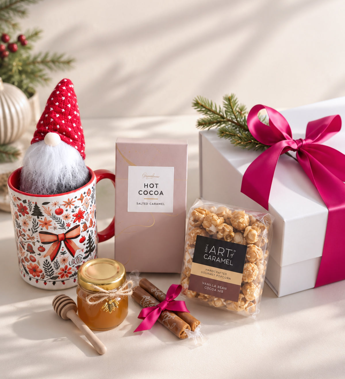 Holiday mug with a red-hat gnome tucked inside, beside hot cocoa, caramel popcorn, a honey jar, caramels and a ribbon-wrapped white gift box