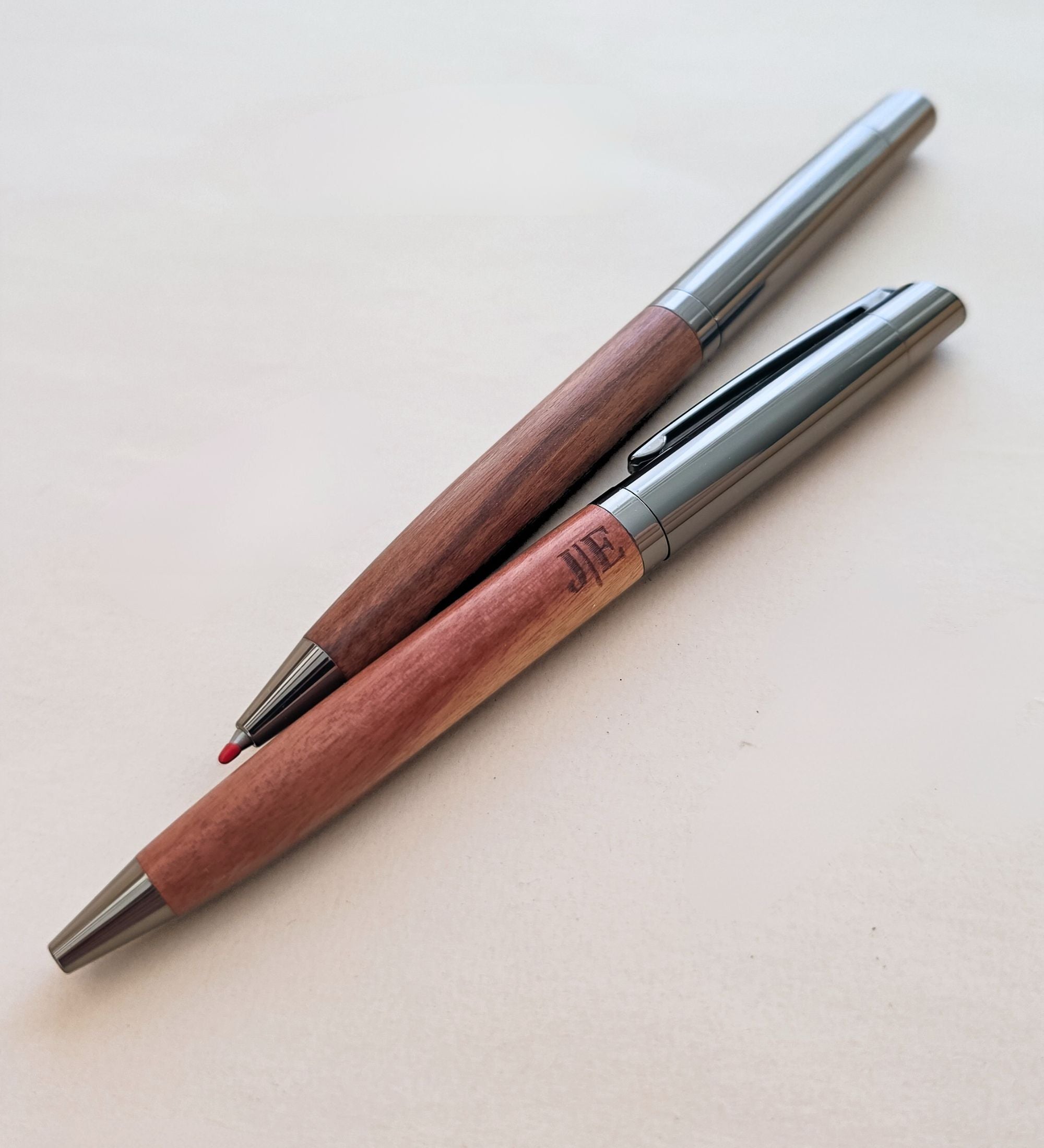 Two acacia pens photographed together, one plain and one etched, showing the difference in finish
