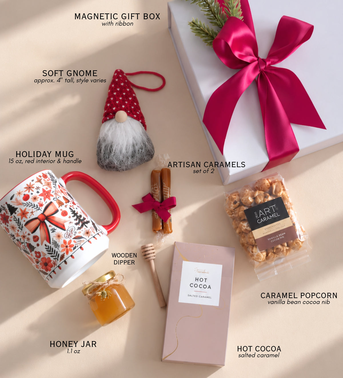 Flat lay of everything in the Christmas gift box: magnetic box with ribbon, holiday mug, gnome, caramels, honey jar with wooden dipper, hot cocoa and caramel popcorn