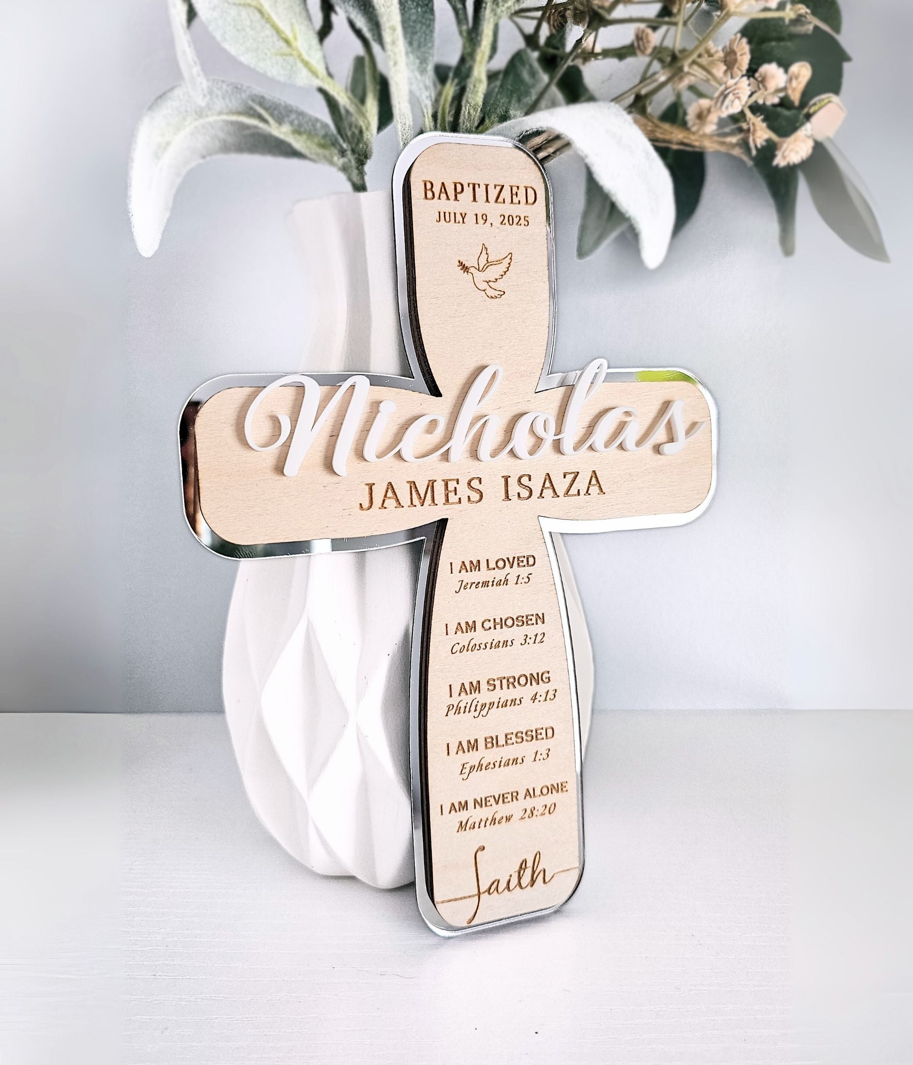 Close-up of engraved birch wood cross with white acrylic name and dove detail
