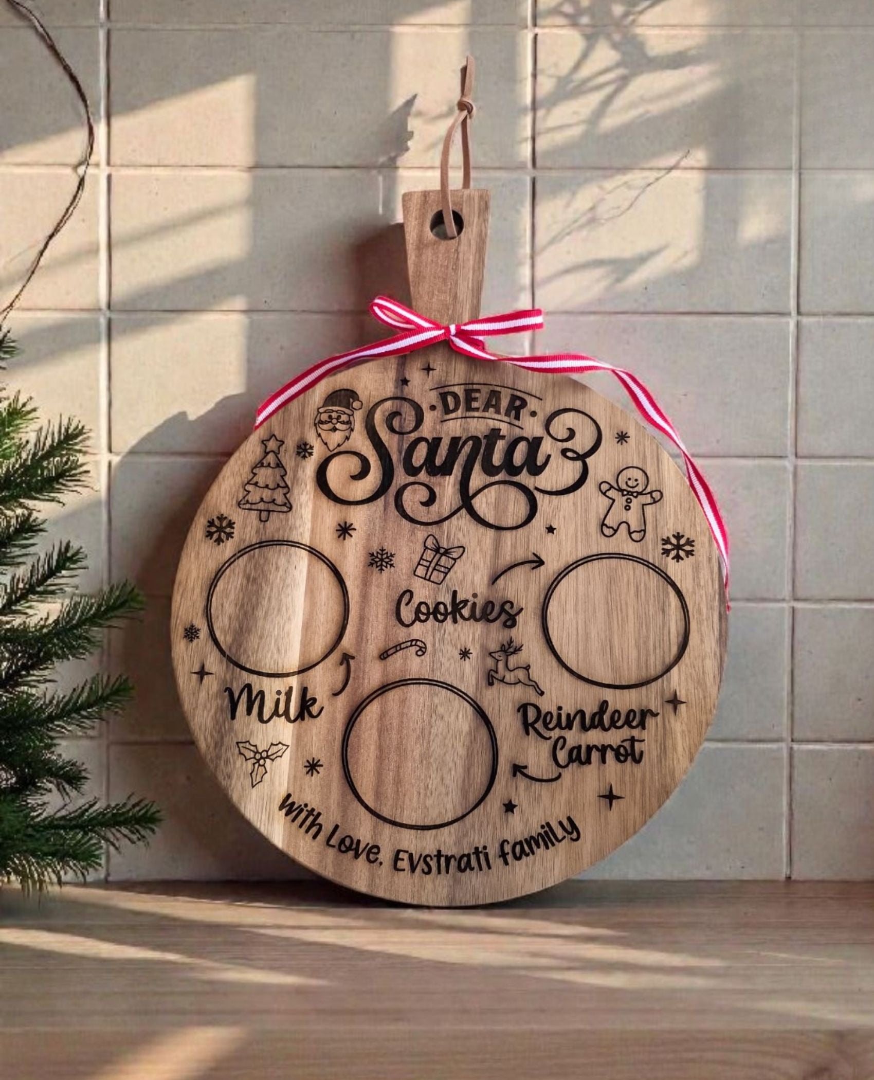 Engraved Christmas Eve board personalized with the family name beneath With Love, finished with a red and white ribbon