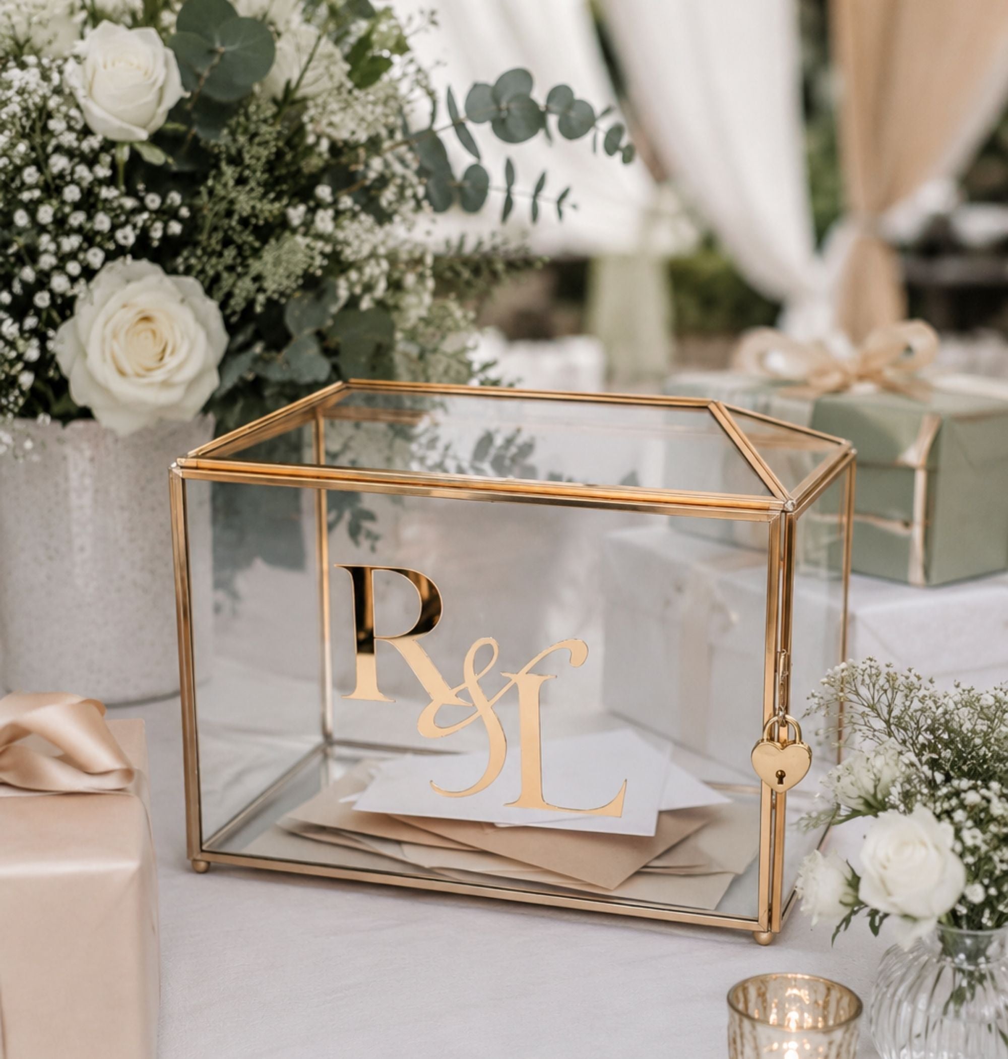 Personalized glass wedding card box with gold brass frame and 3D acrylic monogram on a decorated reception gift table surrounded by white roses and eucalyptus