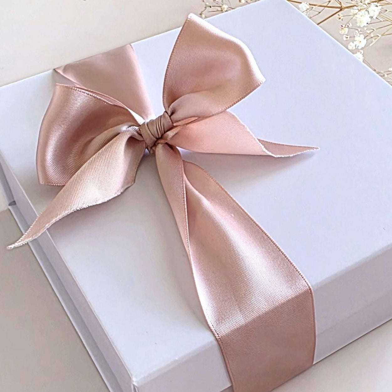 White gift box with a large pink satin bow on a light background