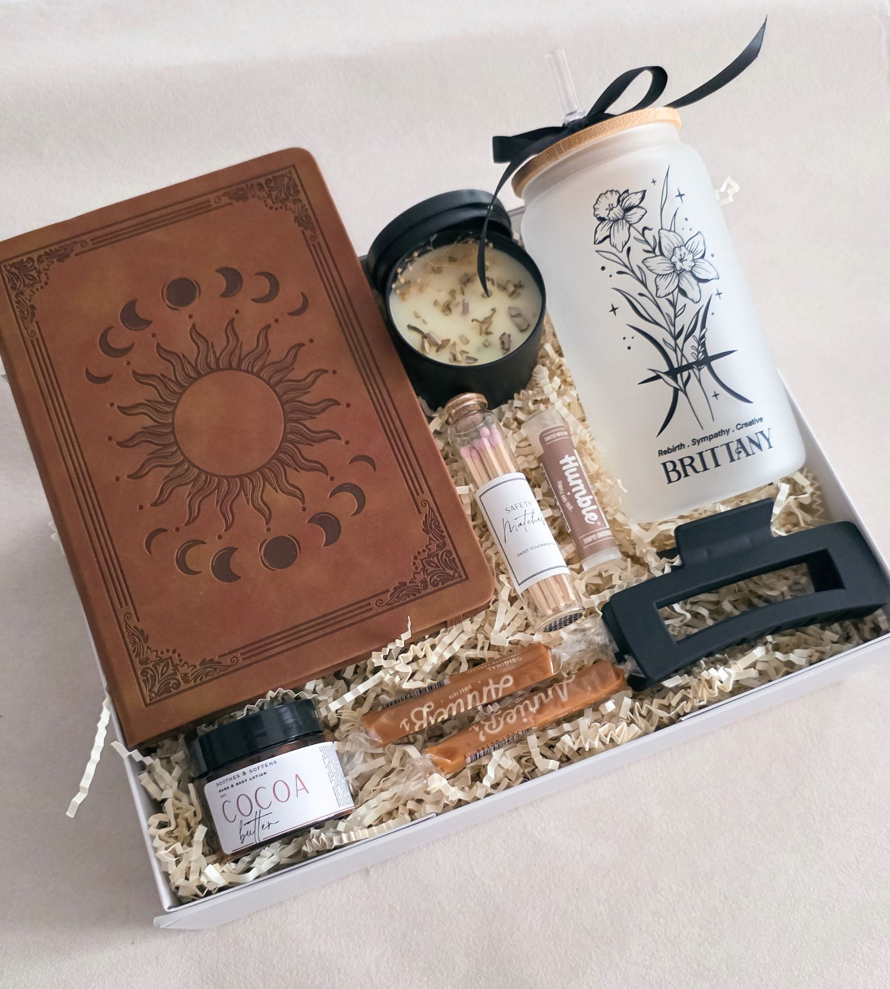 Ultimate zodiac gift box open to show a personalized frosted glass tumbler, hardcover journal, soy candle, and self-care extras