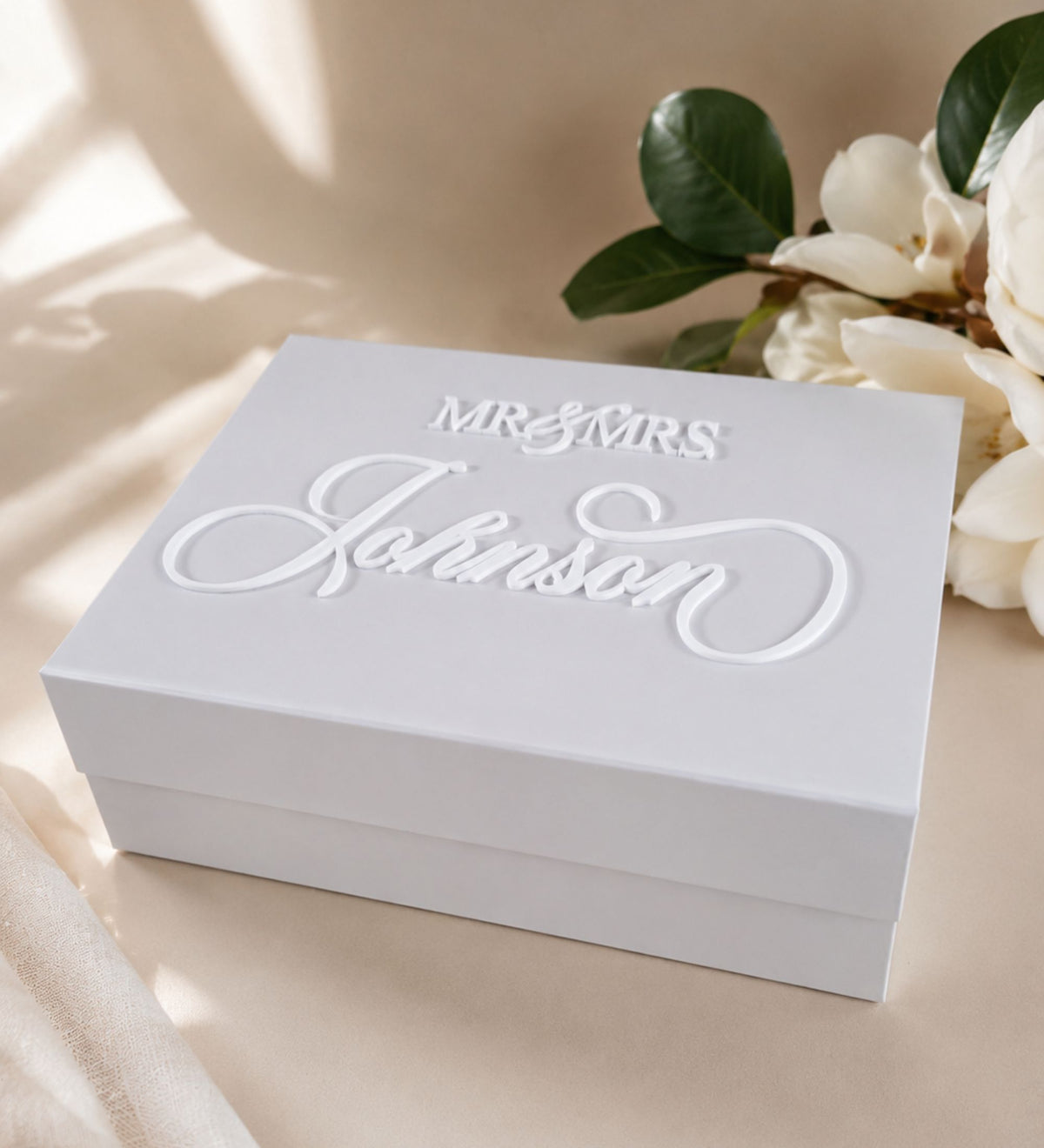 Angled overhead view of the white keepsake box styled with magnolia leaves and cream blossoms