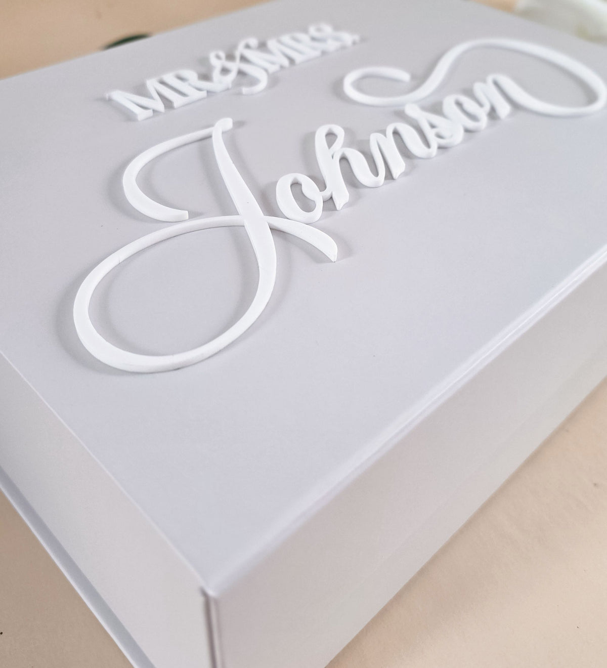 Close-up of the raised white acrylic script on the lid, showing the dimensional edge against the matte box