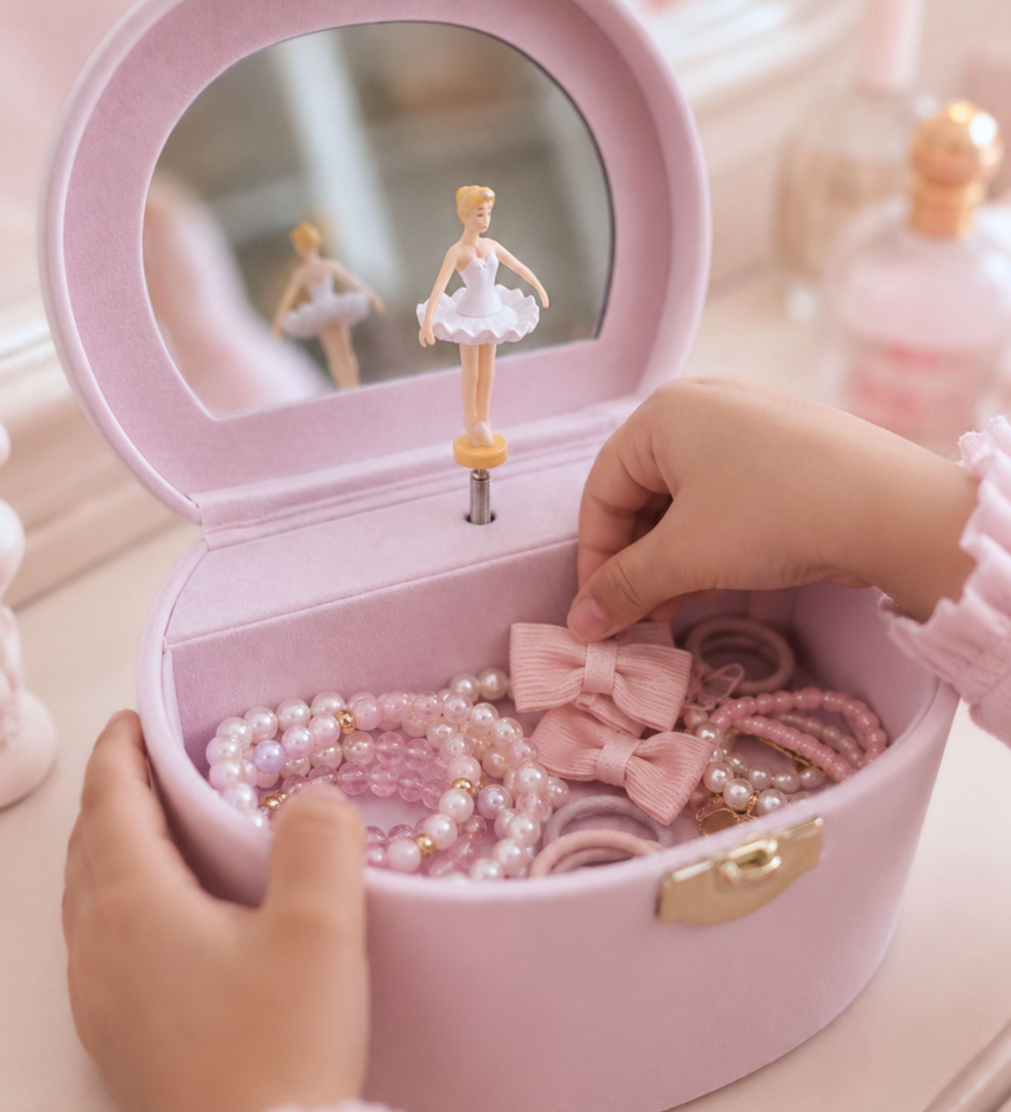 Close-up of pink leatherette jewelry box exterior showing engraved butterfly-font initial and gold carry handle hardware detail